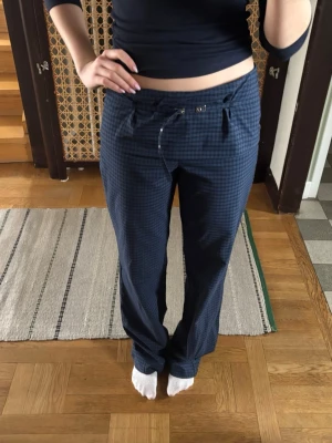 Blårutiga byxor med snörning - Snygga blårutiga byxor med rak passform och snörning i midjan. Byxorna har ett diskret rutmönster och är tillverkade i ett mjukt bomullsmaterial. Perfekta för en chill och stilren look.