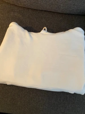 Vit hoodie från J.Lindeberg - Säljer en stilren vit hoodie från J.Lindeberg med diskret broderad logga på bröstet. Hoodien har klassisk huva och är gjord i mjukt bomullsmaterial som känns skönt mot huden. Perfekt för dig som gillar minimalistisk och clean stil.