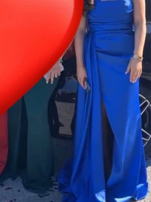 Kornblå långklänning med slits - Säljer denna superfina blåa bal klänningen som endast är använd en gång och är kemtvättad. Klänningen är i ett jätte fint skick och har en slits på sidan och även ett släp. Trianglarna kan även vikas ned för en mer bandå look. Är i storlek 38 men passar även super bra för någon som har storlek 36. Passar superbra till ett bröllop eller bal. Köpt för 3000 men säljs för 1800, priset kan diskuteras vid snabb affär