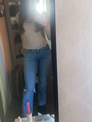 Blås bootcut jeans med hål - Säljer ett par blå bootcut jeans med slitning vid knät. Jeansen är midwaist och storlek 34, säljer då jag inte får på mig dom längre! ❤️de är från Gina tricot 