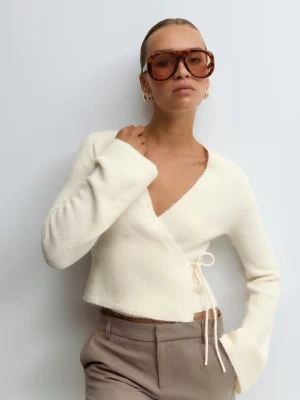 Vit omlottstickad tröja med knytband - Säljer en snygg vit stickad omlott-tröja med knytband i sidan. Tröjan har långa ärmar med lite utsvängd form och en djup v-ringning. Perfekt att matcha med både jeans och kostymbyxor. Materialet ser mjukt och skönt ut. (Den är vitare inte krämvit i verkligheten) och mindre passar mig med S