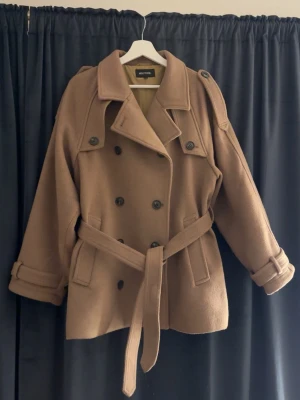 Brun trenchcoat från Meotine ÄKTA Kashmir  - Snygg brun trenchcoat från Meotine med dubbelknäppning, bred krage och axelklaffar. Äkta Kashmir köpt för 4000 och fortfarande helt bra skick använt max 3 gånger. 