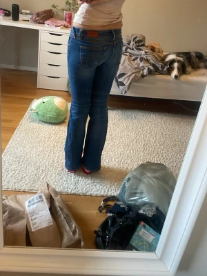 Blå jeans med slitning och hål - Säljer ett par blå jeans med slitningar och ett hål på ena knät. Jeansen har klassisk femficksmodell, låg midja och raka ben. Snygga kontrastsömmar och detaljer vid fickorna. Perfekta för en avslappnad och trendig look. Midja 26 längd 34