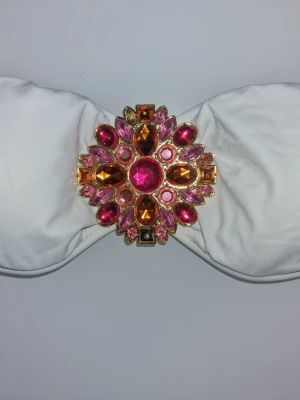 Victoria's Secret vit bikinitopp - Suupersnygg bikiniöverdel i bandeaumodell med brosh framtill. Broschen har stenar i olika nyanser och 1 utav stenarna har ramlat av. Inget man tänker på då det ser ut som en sten med ljusreflektionen. 🩷🤍 Finns ej att köpa längre.