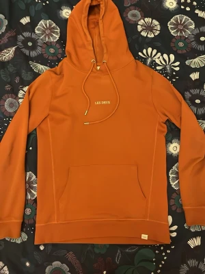 Hoodie Les Deux - Snygg orange hoodie från Les Deux i xs. Någon småfläck som knappt syns som säkert går bort i tvätten (inte testat). Skriv gärna vid frågor!