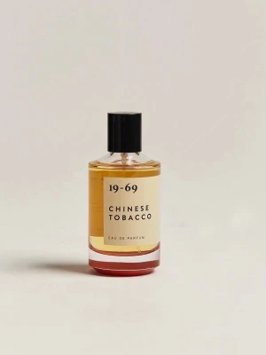 19-69 Chinese Tobacco Eau de Parfum - Parfymflaska med doften Chinese Tobacco från 19-69. Flaskan är genomskinlig med svart lock och etikett i beige med svart text. Innehållet är bärnstensfärgat. En stilren och modern design som passar perfekt i badrumshyllan.