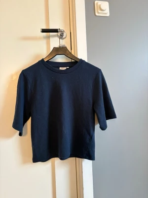 Mörkblå tröja från Nelly - En stilren mörkblå tröja från Nelly med rund halsringning och halvlånga ärmar. 