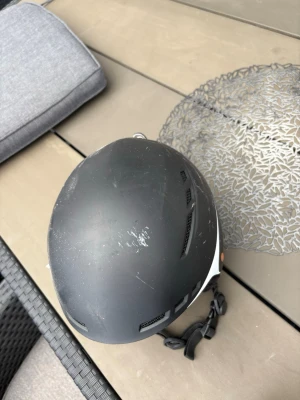 Svart hjälm från Republic - Säljer en svart sporthjälm från Republic med vit kant och flera ventilationshål. Hjälmen har justerbart hakband och snygg, stilren design. Perfekt för olika sportaktiviteter där hjälm krävs. 100 kr per vara.