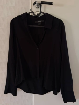 Svart skjorta från Vera moda - Stilren svart skjorta från vera moda med klassisk krage och långa ärmar. Skjortan har knappar framtill och är tillverkad i ett mjukt material som ger en avslappnad känsla. 