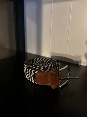 Flätat bälte svart vitt  - Ett riktigt snyggt flätat bälte. Bältet är svart vitt och passar till det mesta. Skicket är otroligt bra då de endast är använt någon enstaka gång. Skriv vid frågor och kolla gärna in min profil för fler bälten och kläder!