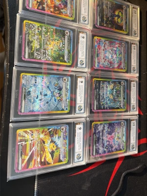 Samling Pokémonkort i hårda fodral - Säljer en samling Pokémonkort, alla graderade och inplastade i hårda fodral från RaukCard. Korten har färgstarka motiv och varierande design, flera med holografiska effekter. Perfekt för samlare som vill ha snygga och skyddade kort.