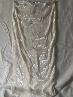Ljusbiege lång paljettkjol från H&M Divided - Säljer en beige långkjol från H&M Divided, täckt med glittriga paljetter. Aldrig använd.