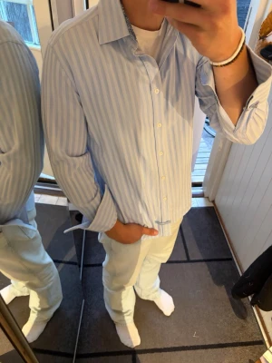 Vitblå randig skjorta från English Laundry - Säljer en tvärfet vit/blå randig skjorta från English Laundry by Christopher Wicks. Skjortan är som ny och har inga skador. Skidorna har coola detaljer på sig. Behöver dock manschetter för att knäppa den helt i armen, men funkar utan också! Skjortan passar mig som vanligtvis kör Medium.