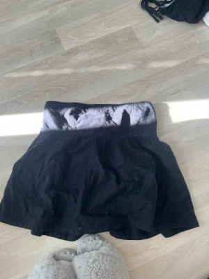 Svart topp från BikBok - Säljer en svart toppl från BikBok med bred resår i midjan och lätt utställd passform. Kjolen är gjord i ett mjukt tyg och har en enkel, stilren look som passar till många olika outfits.