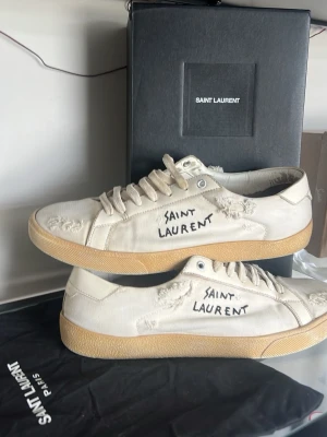 Saint Laurent skor  - Äkta Saint Laurent (SL06) sneakers | Skick: 7,5/10 slitningarna är en del av designen| Storlek 46 fits 47 | Skopåse & kort från Farfetch ingår, kan möjligen fixa box om det är viktigt| Fraktar inom 24H efter köp, på köparens bekostnad 📦 | Hör av dig vid minsta fråga eller fundering 💭