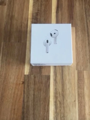Apple AirPods med laddningsetui - Säljer ett par vita Apple AirPods med trådlöst laddningsetui. Snygg och stilren design i blank plast, perfekt för dig som vill ha smidiga hörlurar till mobilen. Originalförpackning och manualer medföljer.