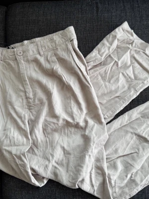 Beige linnebyxor från 157. Herr L. - Säljer ett par nya ljusbeige linnebyxor. Tillverkade i ett tunt och luftigt linnematerial som passar perfekt till sommaren, 55% lin, 45% viskos. Byxorna har raka ben, hög midja och klassisk knappgylf. Storlek L. Från Lager 157. Nya, lappen kvar. Finns inget att anmärka på. NWT. Snyggt avslappnad passform och diskreta fickor framtill.