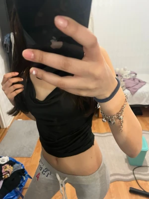 Svart linnetopp med tunna band - Säljer en svart linnetopp med tunna axelband och snygg draperad urringning. Toppen är croppad och har en tight passform som framhäver midjan. Perfekt att styla med jeans eller kjol för en trendig look.