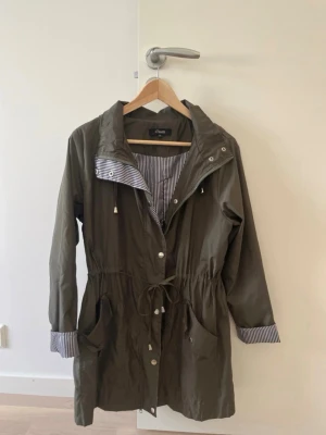 Grön regnjacka  - En vindjacka. Jackan tål lite vatten men inte mycket regn. Ganska stor för att vara storlek S. Nyskick.