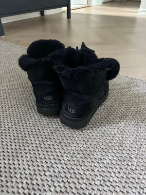 UGG - Säljer ett par svarta UGG skor i storlek 37. De är svarta och har en rosett där fram. De har dock lite defekter som syns på bild 2 och 3 men eftersom de är på insidan av skorn så tänker man inte jättemycket på det💞