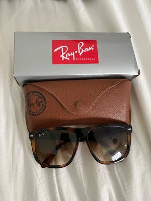 Ray-Ban bruna boifriend  solglasögon - Säljer ett par klassiska Ray-Ban Wayfarer solglasögon med brunmelerad båge och mörka glas. Kommer med originalfodral i brunt skinn och Ray-Ban box. Perfekta för dig som vill ha en tidlös och ikonisk look.
