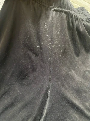 Al Nassr svart träningsset Adidas - Säljer ett svart träningsset från Adidas med Al Nassr FC-logga på tröjan. Setet har vita detaljer och tryck, samt elastisk midja på byxorna. Materialet är mjukt och andas, perfekt för fotbollsträning eller gym. Snygg och sportig design med klubbmärke och sponsortryck.