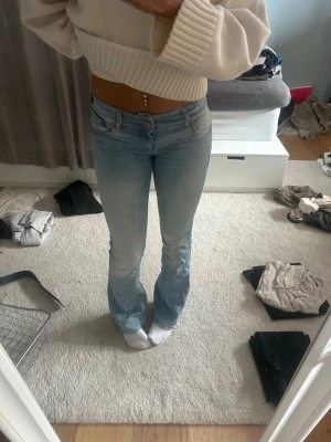 Ljusblå bootcut jeans - Säljer ett par ljusblå bootcut jeans med klassisk femficksdesign och låg midja. Jeansen har en snygg tvättad look och är tillverkade i ett stretchigt denimtyg som sitter bekvämt. Perfekta för dig som gillar en avslappnad men trendig stil.