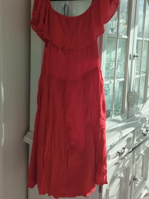 Krinklad röd  klänning Lindex XL - Snygg röd offshoulder klänning från Lindex i storlek XL. Klänningen har volang upptill och är tillverkad i ett lätt, skrynkligt tyg( krinklad) som ger en avslappnad känsla. Vrid klänningen när det är fuktigt för att få skrynkeleffekten. 