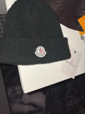 Svart ribbstickad mössa från Moncler - Moncler mössa i väldigt bra skick! Endast använd ett fåtal gånger 