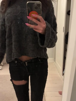 Mörkgrå stickad croppad tröja - Mysig mörkgrå stickad tröja med croppad passform och breda ärmar. Tröjan har en avslappnad siluett och grovstickad struktur som ger en trendig look. Perfekt att matcha med höga jeans eller kjol.