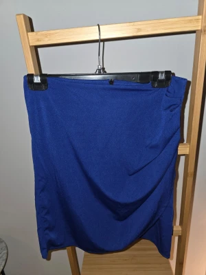 Kornblå kortkjol i stretchigt tyg - En enkel och stilren kornblå kortkjol i stretchigt material. Kjolen har en rak passform och slutar ovanför knäna. Perfekt att matcha med en t-shirt eller blus för en trendig look.