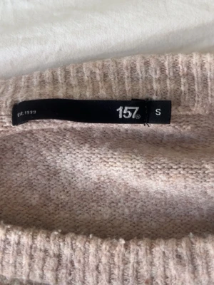 Beige stickad tröja från 157 - Heej!!💞 Säljer en mysig beige stickad tröja från 157 med rund halsringning och ribbade muddar. Tröjan har en enkel och avslappnad passform, perfekt för lager på lager. !!Använd några gånger så lite nopprig men inte så värst!!  Materialet känns mjukt och behagligt mot huden!🥰Pris kan diskuteras då jag inte har någon användning av tröjan!