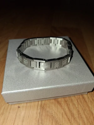 Lacoste armband i rostfritt stål - Snyggt armband i silverfärgat rostfritt stål med rektangulära länkar och diskreta mönstrade detaljer på vissa länkar. Armbandet har en smidig låsning och passar perfekt för dig som gillar en stilren och modern look.