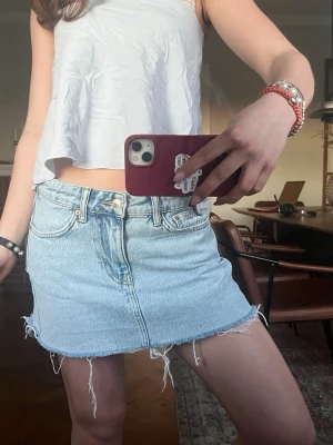 Lågmidjad jeanskjol  - Lågmidjad jeanskjol från Gina. Väldigt bra skick. Går att klippa kortare i och med att den är fransad. 