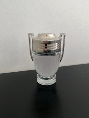 Paco Rabanne Invictus parfym - Säljer en Paco Rabanne Invictus parfym i en unik troféformad flaska med silverfärgade detaljer och genomskinligt glas. Doften är fräsch och maskulin, perfekt för dig som vill sticka ut. Kommer med originalkartong. Bara använd ett fåtal gånger så den är i princip full