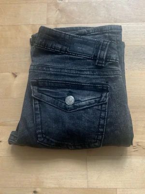 Svarta jeans från Perfect Jeans - Snygga svarta jeans från Perfect Jeans i storlek 36. Jeansen har en cool tvättad look, klassisk femficksmodell och en ficka med lock och knapp bak. Tillverkade i stretchigt denim för skön passform.