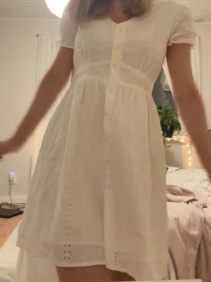 Vit kortklänning med spetsdetaljer - Söt vit kortklänning med spetsdetaljer och knappar framtill. Klänningen har korta ärmar och v-ringad hals, samt ett luftigt och lätt material som passar perfekt till varma dagar. Stilren och romantisk design som är enkel att matcha. Jättefin till studenten eller skolavslutningen. Jag köpte den till studenten och tyckte om den väldigt mycket men valde sen en annan väldigt lik. Den är från LTB men köpt på Sellpy. Den är i mycket bra skick och är som ny.