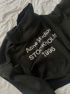 Svart hoodie Acne Studios Stockholm - Aldrig använd. Svart hoodie från Acne Studios med trycket 'Acne Studios STOCKHOLM 1996' i vitt på ryggen. Klassisk passform med huva och ribbade muddar. Jätte skönt material. Pris kan såklart diskuteras!! 