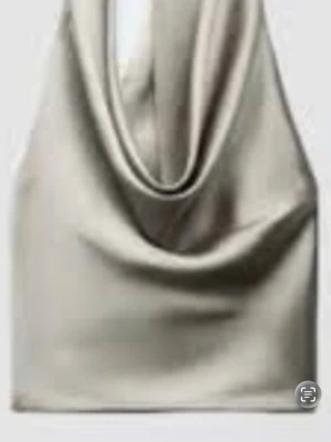 Silvrig axelremsväska i satin - Trendig handväska i silvrigt satinmaterial med mjuk, slouchy form och bred axelrem. Väskan har minimalistisk design utan synliga detaljer eller logga, vilket ger en clean och modern look. Perfekt för dig som gillar stilrena accessoarer.