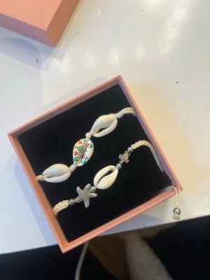 Vita snäckarmband med pärldetaljer - Två semester armband som är köpa utomlands. Super fina och knappt använda. Skriv vid frågor och pris kan diskuteras! (Finns även på Vinted, samma användarnamn)💞💞