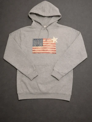Grå hoodie med amerikansk flagga - Grå Hoodie med en klassisk Amerikansk flagga och vit stjärna som tryck😀⛱️ Kan köpas via hemsida också.⛳️ TikTok=Riviere Noir. Pris kan inte förhandlas men var inte rädd att ställa frågor!