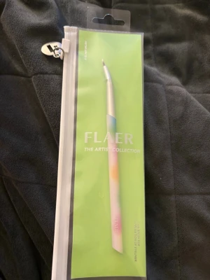 Flaer ögonskuggsborste pastell - Säljer en ögonskuggsborste från Flaer The Artist Collection. Borsten har ett elegant handtag i pastellfärger med inslag av blått, rosa och gult. Kommer i en praktisk förvaringspåse. Perfekt för detaljerad applicering av ögonskugga.