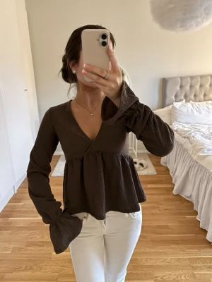 Volang topp - Mörkbrun omlottopp med v-ringning och långa, vida ärmar. Helt ny och använd en gång bara!! 🖤