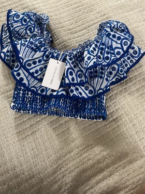 Ny trendig volangtopp  - Supersöt ny volangtopp från Design by Amor i storlek s. Toppen bred volang runt axlarna och smockad resår nedtill. Går att ha som bandeau, one shoulder eller som ”vanligt” med två ”axlar”🤍