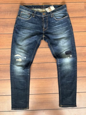 Nudie jeans - Ett par riktigt feta nudie jeans ifrån deras replika designer. Med sjyssta fades, inga defekter lagningarna är endast design.                                         Slim passform (Tight Terry 36/30). Men passar mer som 34/32.                                                        Hör gärna av er vid någon fråga! Finns flera feta liknande plagg på min profil!