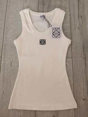 Vit ribbad linnetopp från Loewe - Säljer en stilren vit ribbad linnetopp från Loewe med broderad logga i svart framtill. 