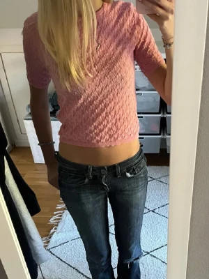 Rosa stickad topp från Zara - Söt rosa stickad topp från Zara med korta ärmar och ett diskret mönster i strukturen. Toppen är croppad och har en rund halsringning. Perfekt för dig som gillar en feminin och trendig stil.