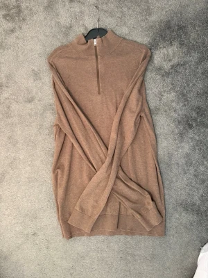 Beige halvzip tröja från selected Home  - Snygg beige tröja med halvzip och hög krage. Tillverkad i tunn, mjuk stickning som passar perfekt för lager på lager. Långärmad modell med ribbade muddar vid ärmslut och nederkant. Enkel och stilren design som funkar till det mesta.