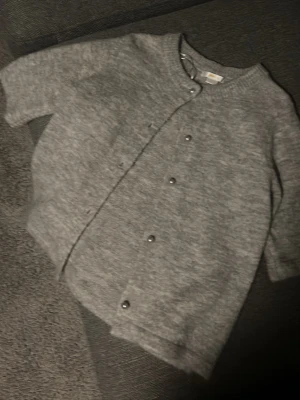 Grå kofta med pärlknappar från Gina tricot i ny skick - Mysig grå kofta från Gina tricot med rund  pärlknappar framtill. Koftan är kortärmad och i nyskick