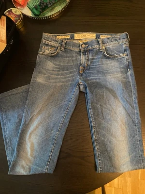 Blå raka jeans med ljusa slitningar - Snygga blå jeans jachob cohen jeans med raka ben och coola ljusa slitningar framtill. Klassisk femficksmodell med detaljerade sömmar på bakfickan. Jeansen har normalhög midja och stängs med knapp och dragkedja. Perfekta för en avslappnad och trendig look.